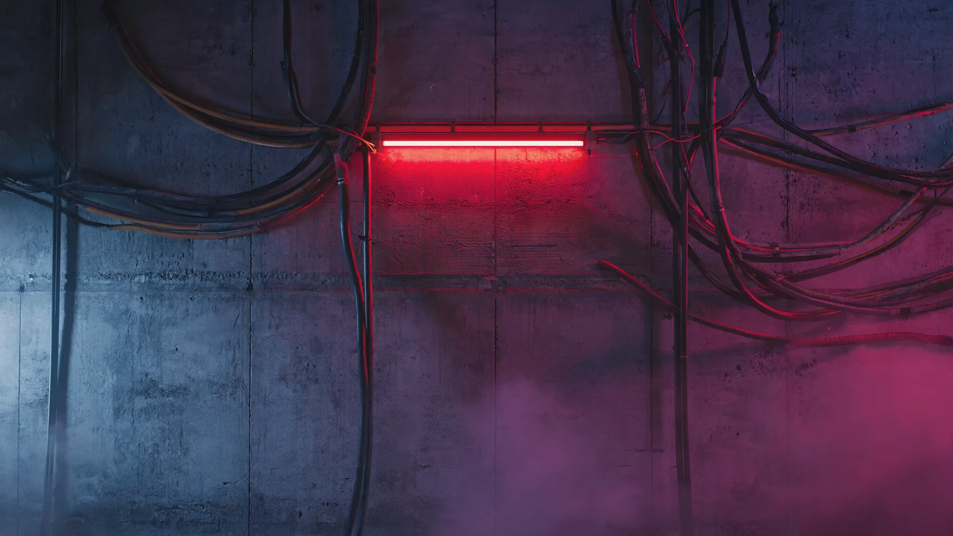 Concrete interior lit by a pink neon tube and hanging cables