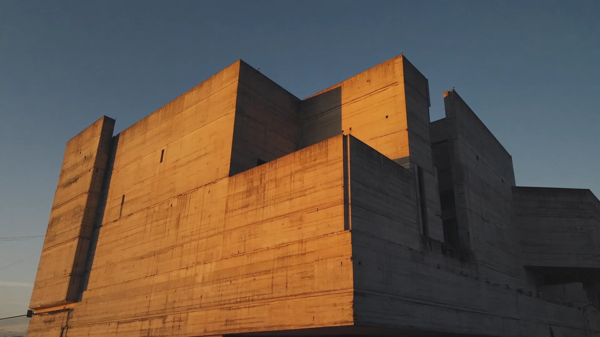 Raw concrete facade lit orange by the low sun