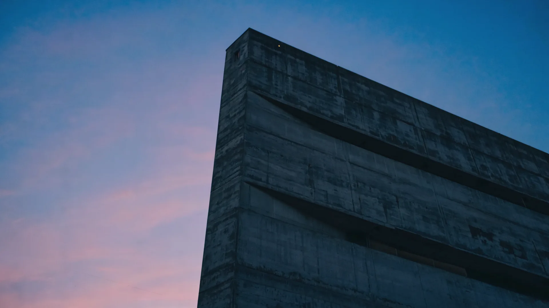 Brutalist concrete block silhouetted against a violet dusk sky